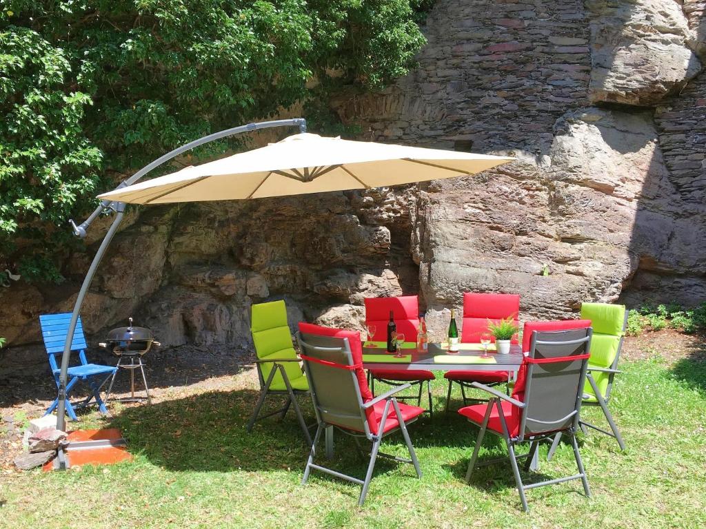 a table and chairs with an umbrella and a grill at Ferienhaus Alte Mühle in Zell an der Mosel