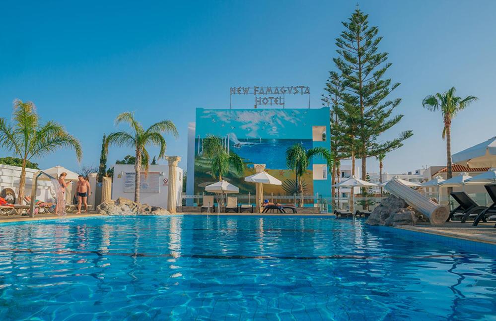 a large swimming pool in a resort with palm trees at New Famagusta Hotel & Suites in Ayia Napa