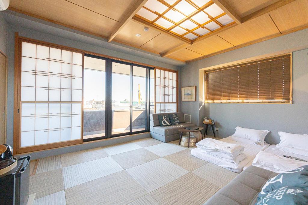 a room with a bed and a couch and windows at 灯光旅館 Light hotel in Tokyo