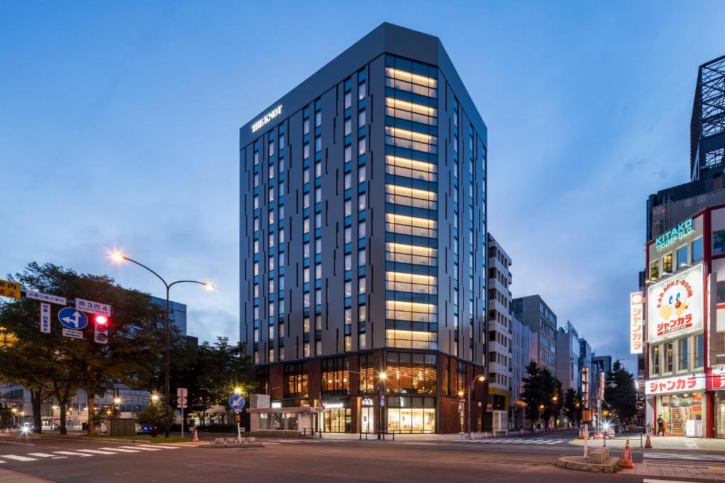 a tall building on a city street at night at THE KNOT SAPPORO in Sapporo