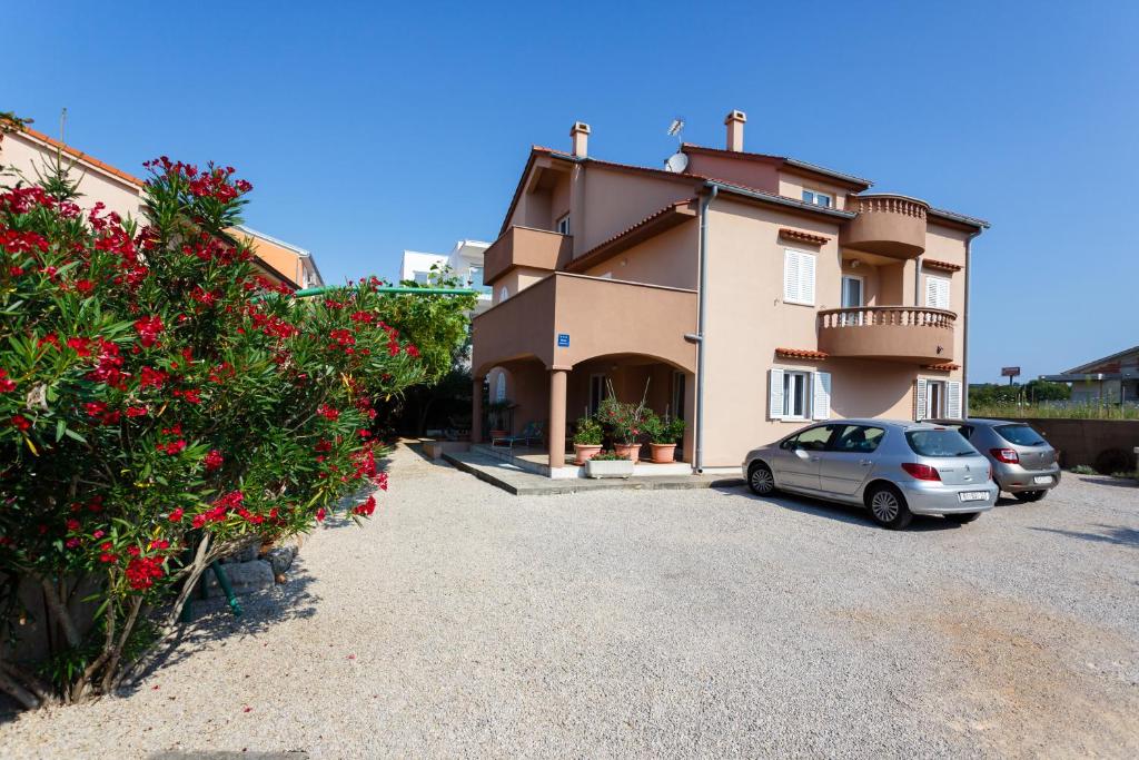 ein Haus mit zwei Autos, die in einer Einfahrt geparkt sind in der Unterkunft Apartments Zdravka in Krk