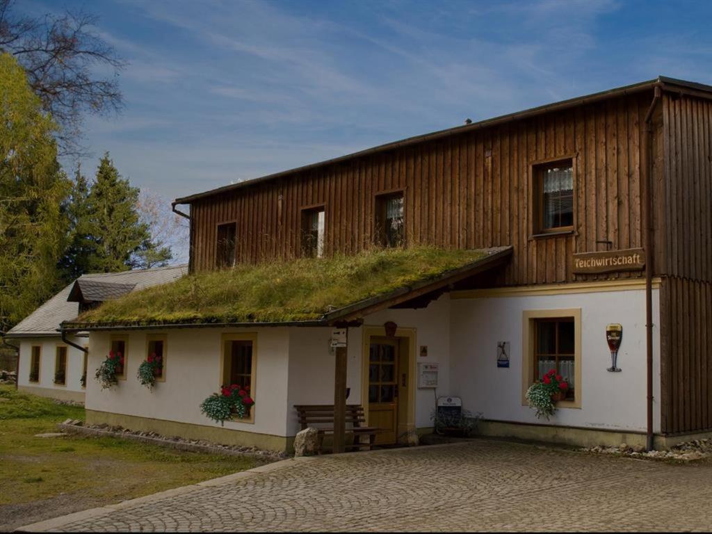 una casa con techo de hierba y porche en Wiesner's Teichwirtschaft, en Scheibenberg