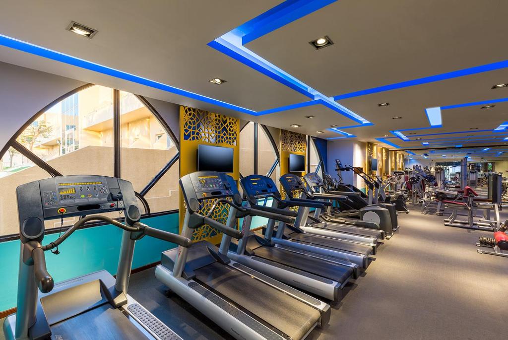 a gym with rows of treadmills and machines at Metropolitan Al Mafraq Hotel in Abu Dhabi