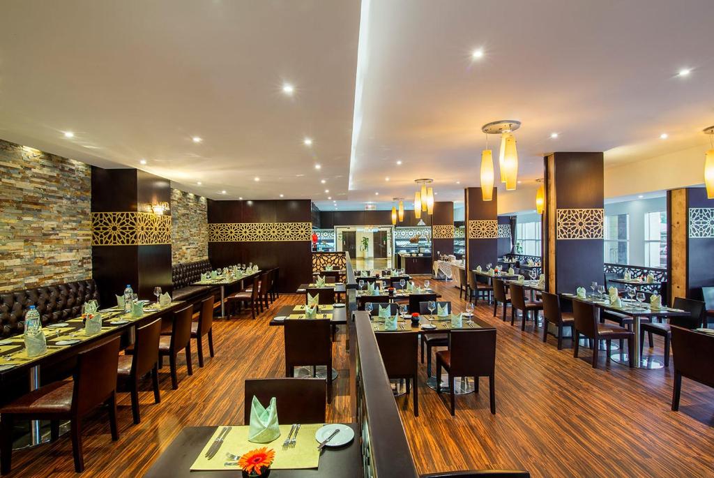 a dining room with tables and chairs in a restaurant at Metropolitan Al Mafraq Hotel in Abu Dhabi