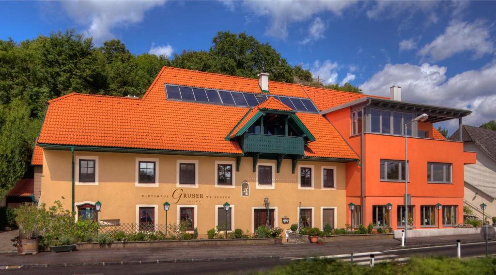 ein Gebäude mit einem orangenen Dach mit Sonnenkollektoren darauf in der Unterkunft Wirtshaus Gruber Weitenegg in Emmersdorf an der Donau