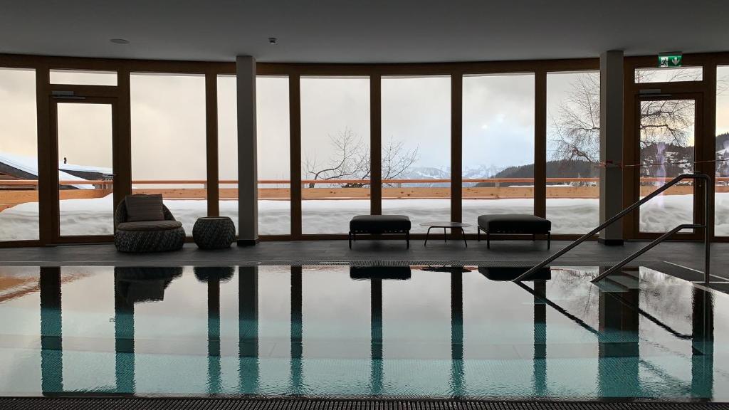 ein Pool mit zwei Stühlen in einem Gebäude in der Unterkunft VIU Hotel Villars in Villars-sur-Ollon