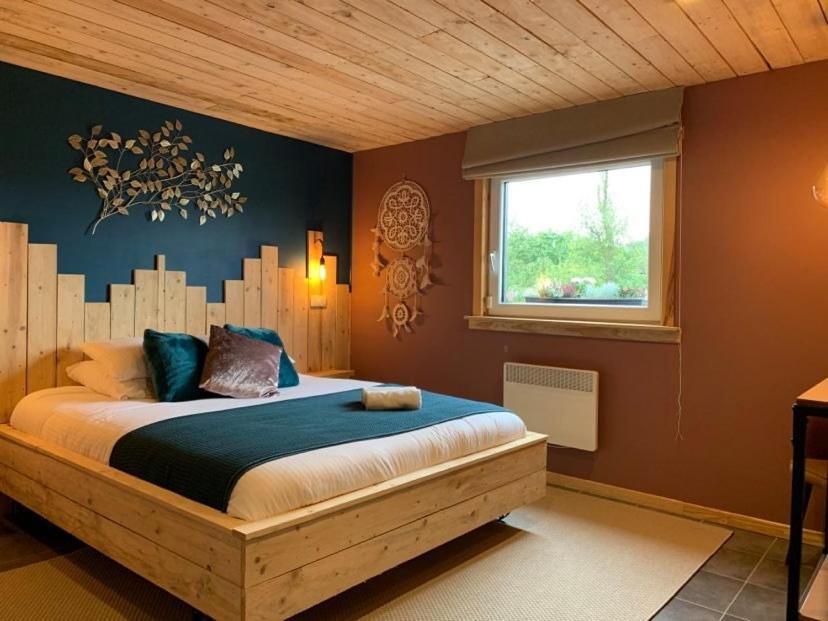 una camera con letto con testiera in legno e finestra di Le Soleil Couchant/Chambre d'hôtes a Givet