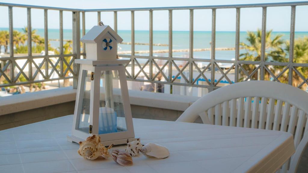 uma mesa com um farol numa varanda com praia em I SUONI DEL MARE em Porto San Giorgio