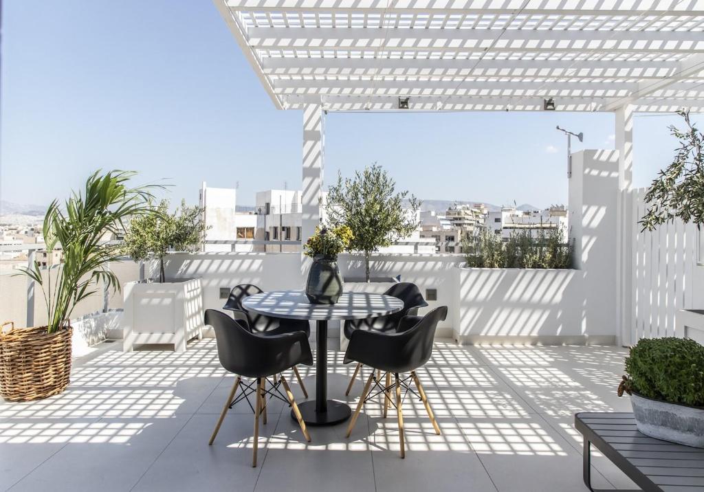 a patio with a table and chairs on a roof at Gallery Suites & Residences in Piraeus