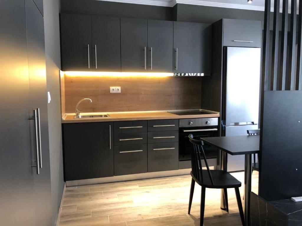 a kitchen with black cabinets and a table and a sink at Stamatina’s Luxury Apartments (central) in Alexandroupoli