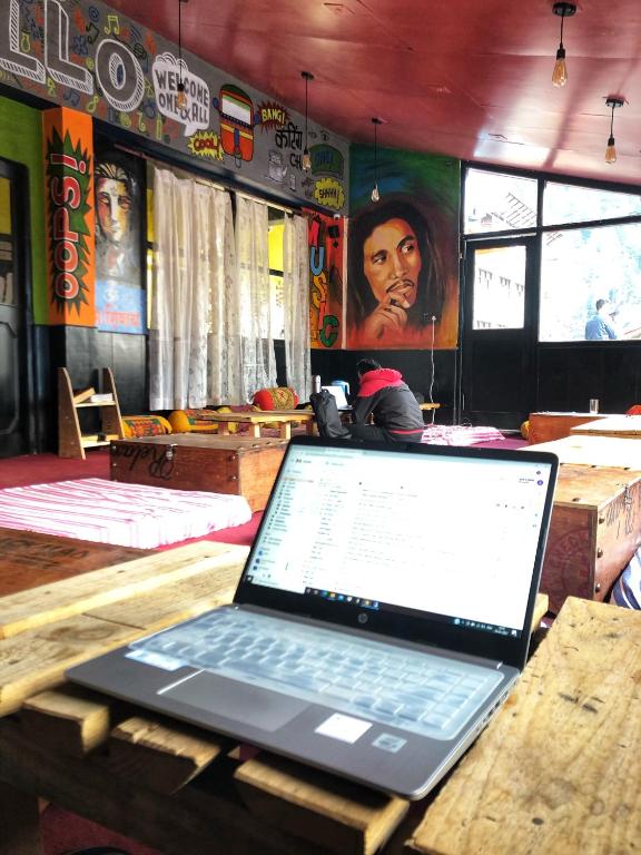 un computer portatile seduto su un tavolo di legno in un ristorante di La Vaca India Manali a Manāli