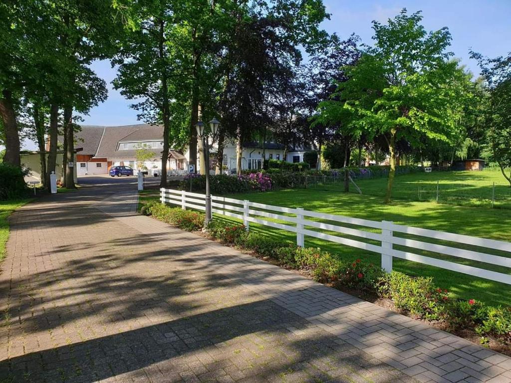 a white fence next to a field with trees at Hotel Weinhof Groß Mackenstedt in Stuhr