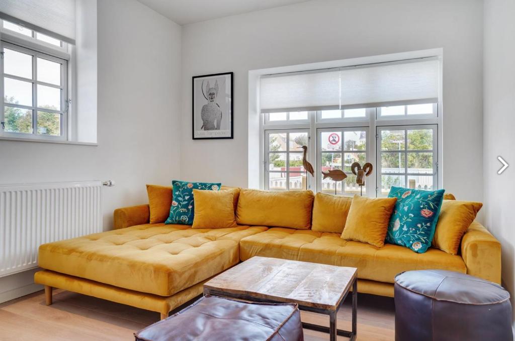 a living room with a yellow couch and blue pillows at 2 Centralt beliggende og lyst indrettet lejlighed in Skagen