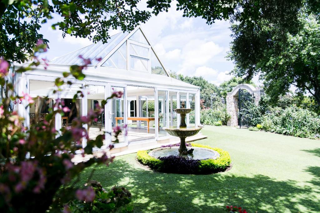 a garden with a fountain in front of a house at Burkleigh House in Johannesburg