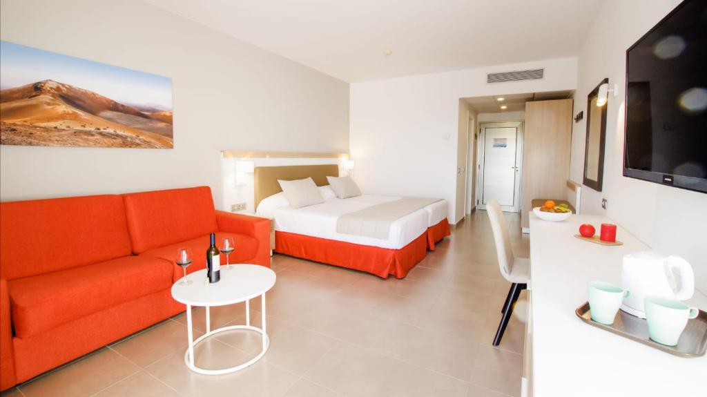 a hotel room with a bed and a couch and a table at Hotel Lanzarote Village in Puerto del Carmen