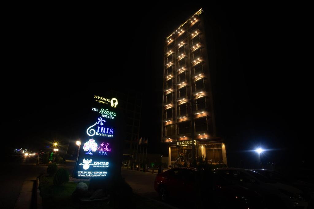 a tall building with a sign in front of it at night at Hyksos Hotel in Erbil