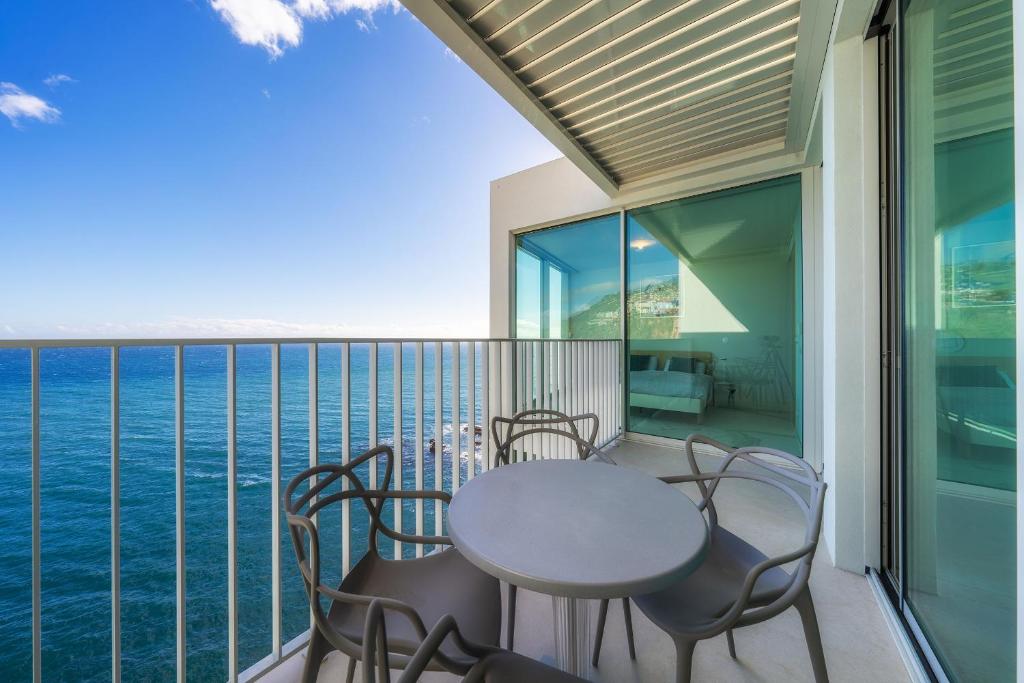 een balkon met een tafel en stoelen en de oceaan bij Barreirinha Front-Line Sea View II by HR Madeira in Funchal