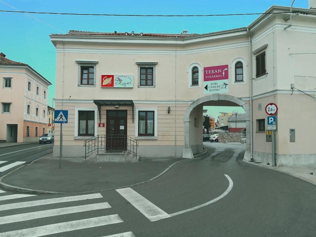 un gran edificio blanco con un arco en una calle en Gostilna pri Dragici, gostilna s prenočišči, d.o.o., en Sežana