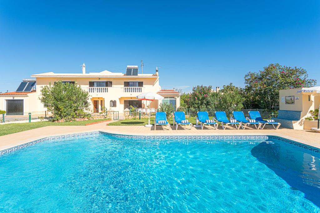 a swimming pool with blue chairs and a house at Villa Misofia in Almancil