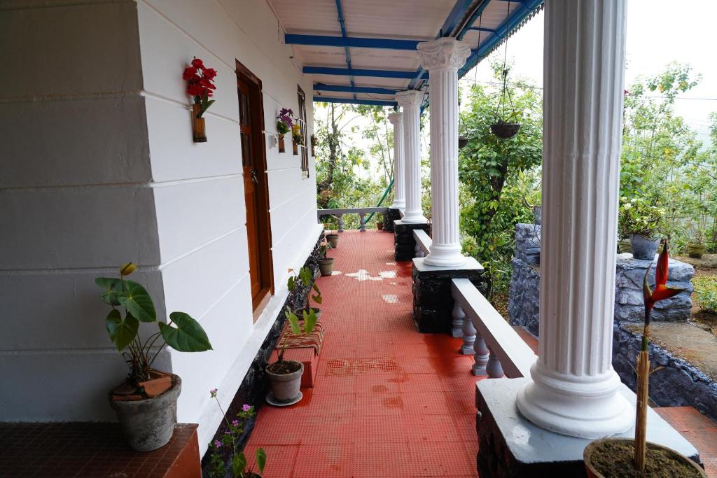 une terrasse couverte avec colonnes blanches et carrelage rouge au sol dans l'établissement Bison Valley Estate, à Valparai