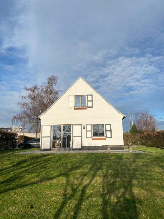 a white house sitting on top of a lush green field at Vakantiehuis Cas.tard in Zillebeke