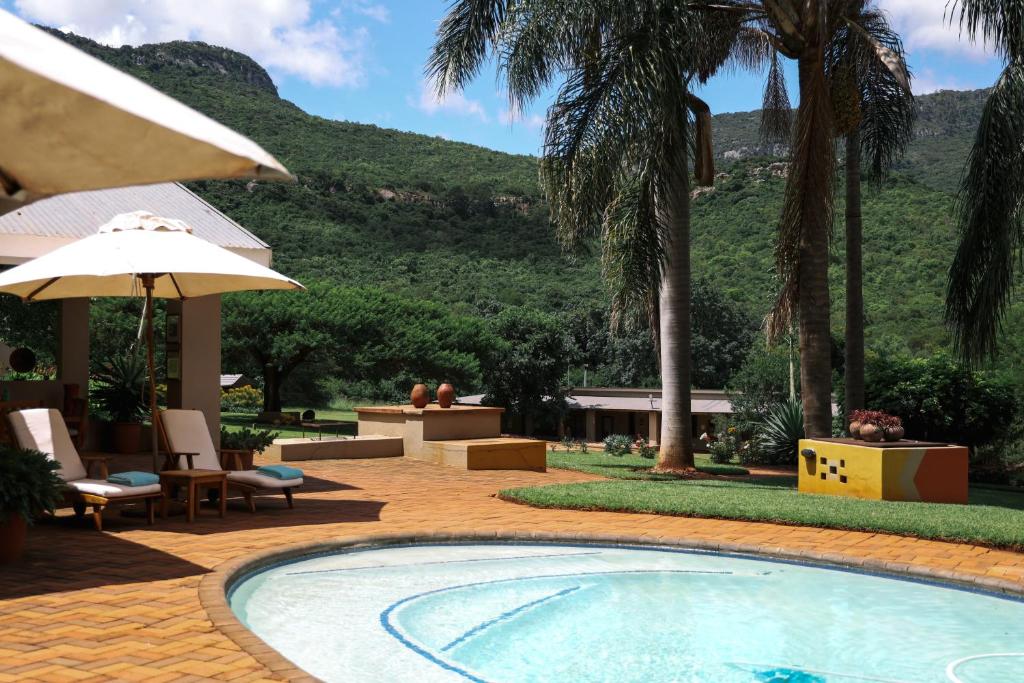a swimming pool with a table and chairs and an umbrella at Madi a Thavha Mountain Lodge in Louis Trichardt