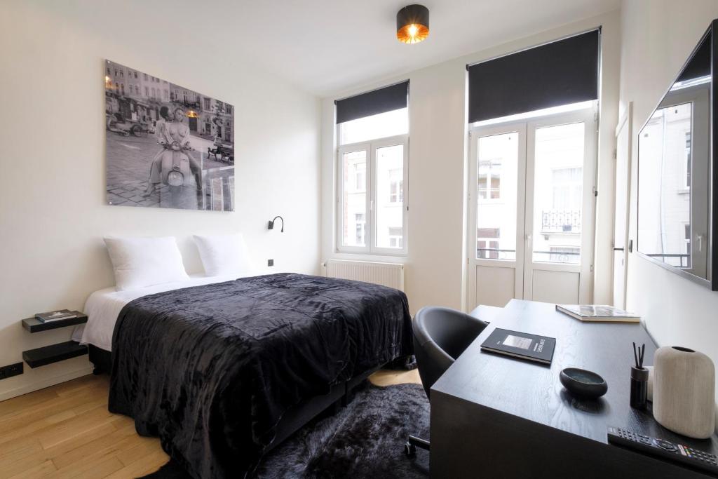 1 dormitorio con cama, escritorio y ventana en The Good House, en Bruselas