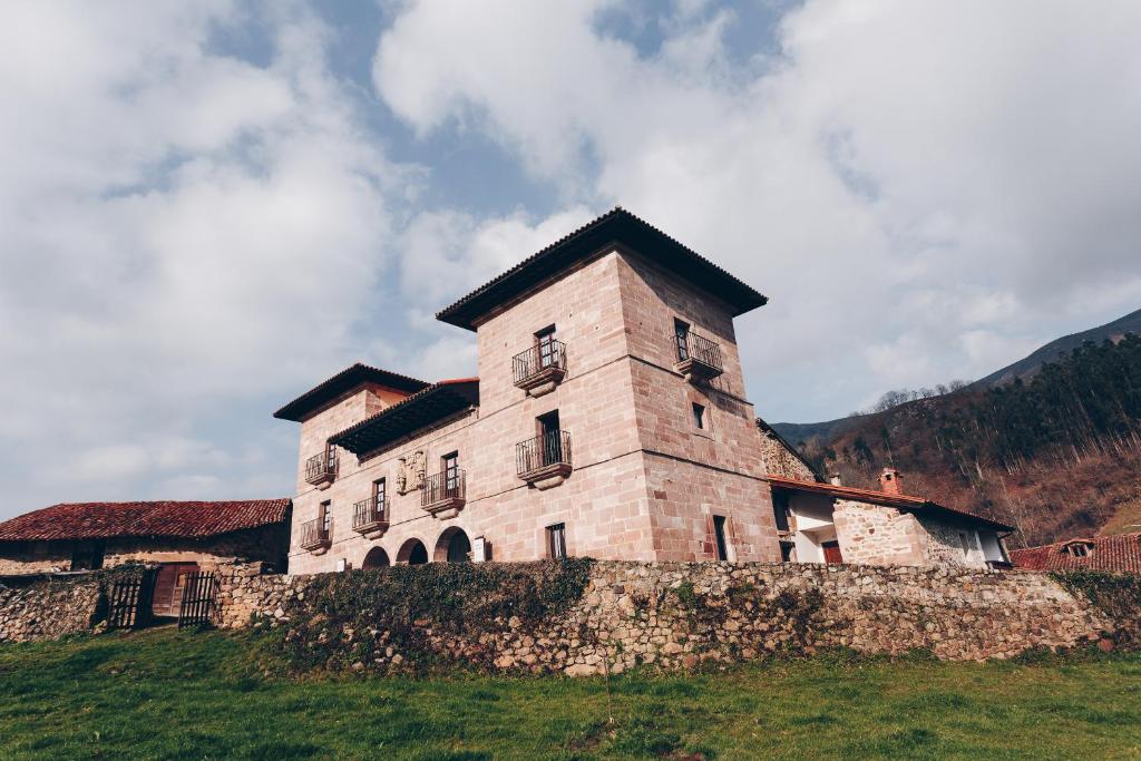 un gran edificio de ladrillo en una colina con césped en Arha Casona de Carmona (Antiguo Parador de Carmona-Cantabria), en Carmona