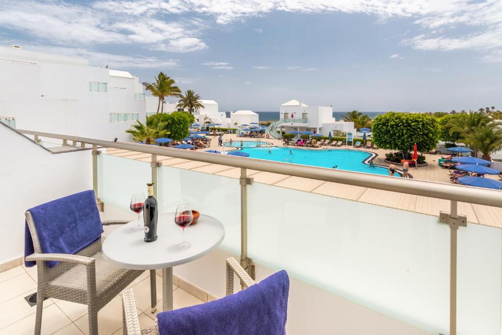 a balcony with a table and chairs and a pool at Hotel Lanzarote Village in Puerto del Carmen