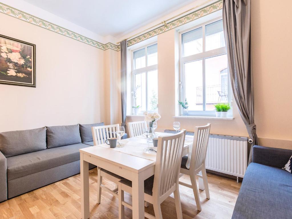 a living room with a table and chairs and a couch at VacationClub - Willa Carmen Apartment 3 in Świnoujście