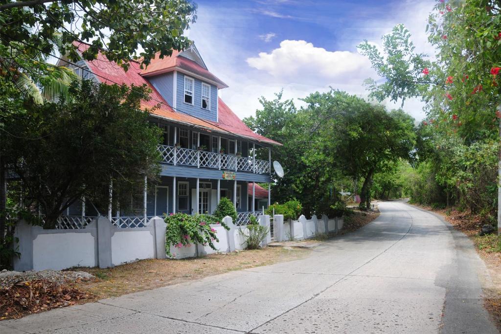 ein blaues Haus mit einem weißen Zaun neben einer Straße in der Unterkunft Coconut Paradise Lodge in San Andrés