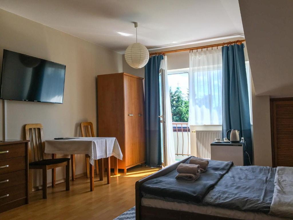 a bedroom with a bed and a table and a television at Willa Zdrój in Ciechocinek