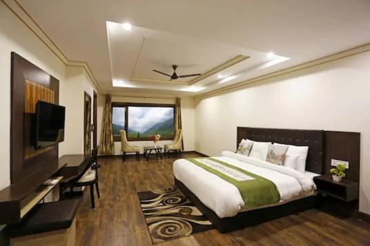 a bedroom with a large bed and a television at Snow Bloom Resort in Manāli