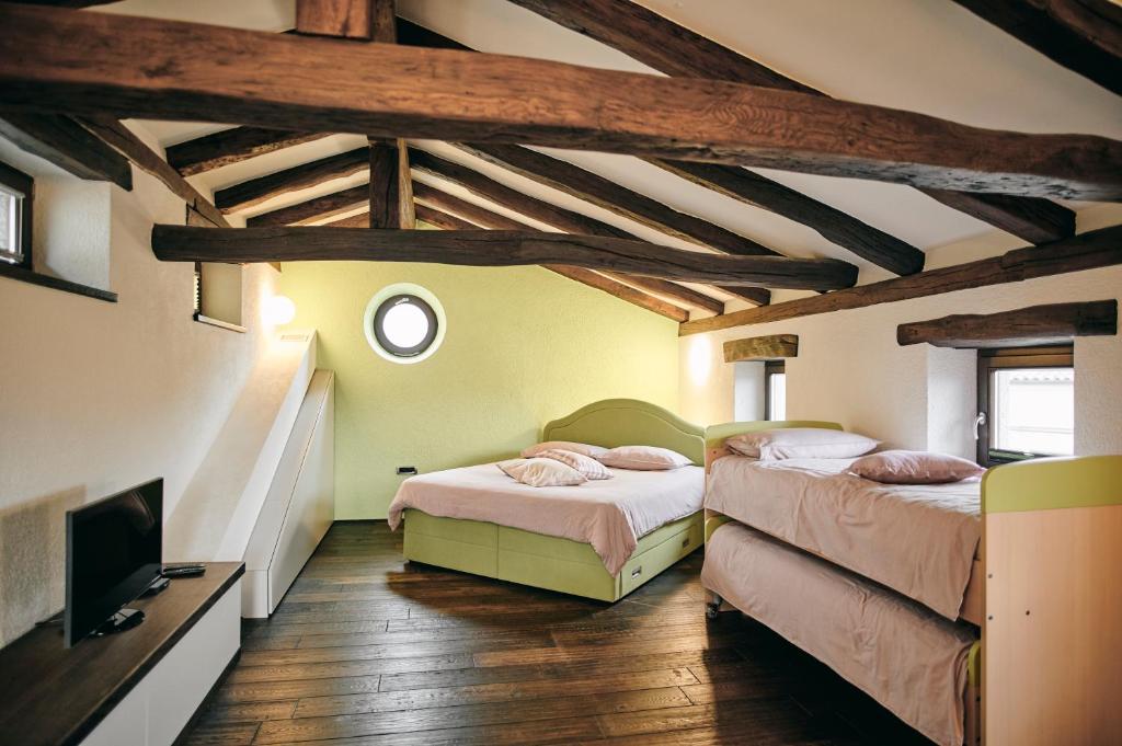 a room with two beds and a tv in it at Tmbin's barn - nature, horses, family in Sežana