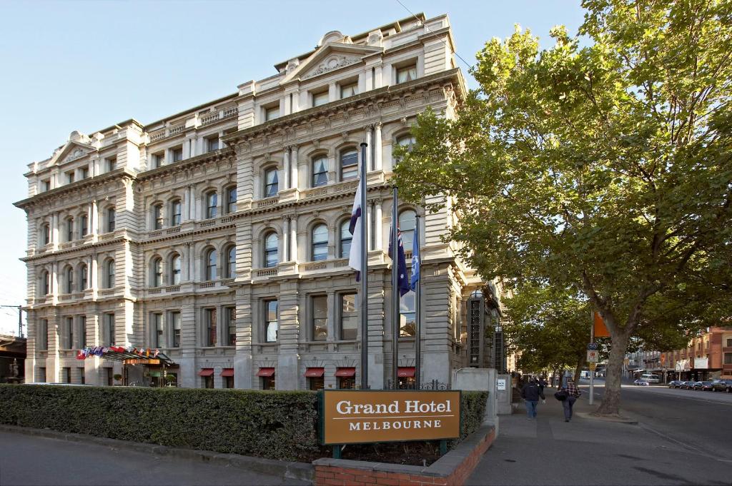 a large white building with a sign in front of it at Grand Hotel Melbourne in Melbourne