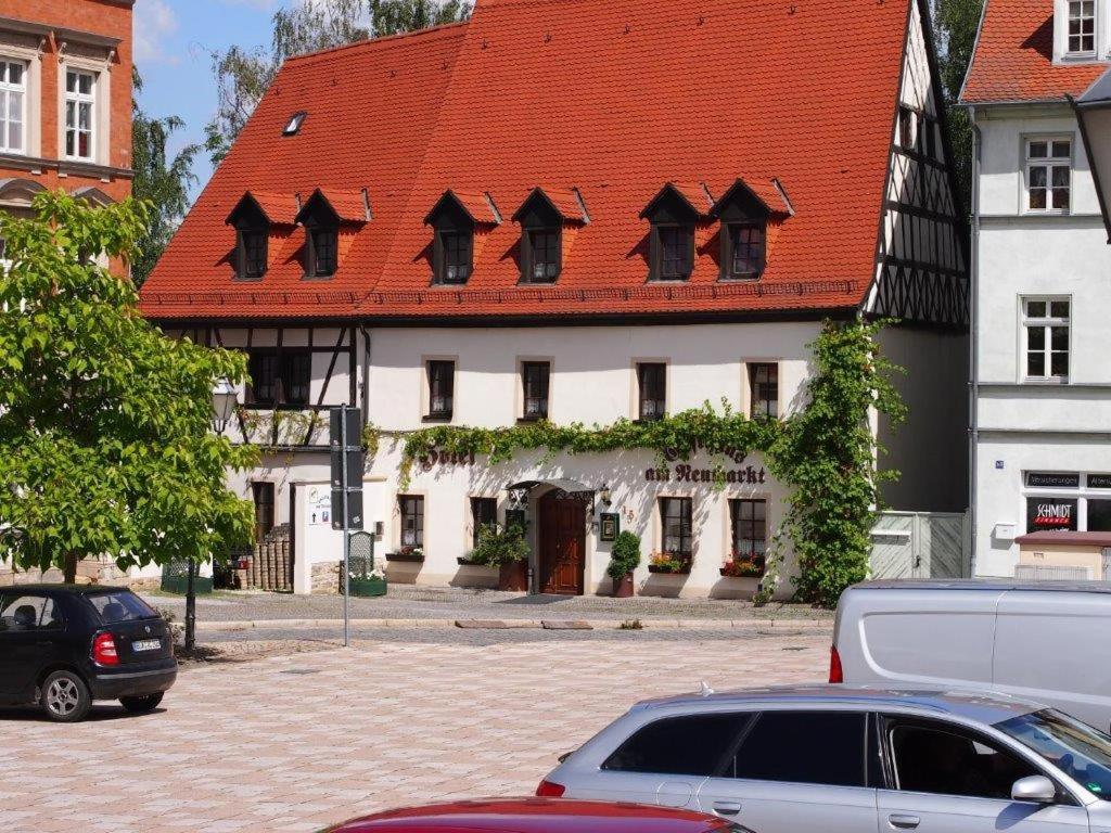 un edificio con techo rojo con coches aparcados delante en Hotel am Neumarkt en Zeitz