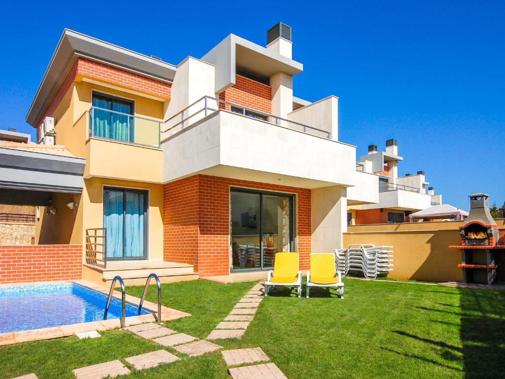 V4, Villa Jardins Branqueira near Beach, Albufeira في ألبوفيرا: بيت فيه مسبح و كرسيين اصفر