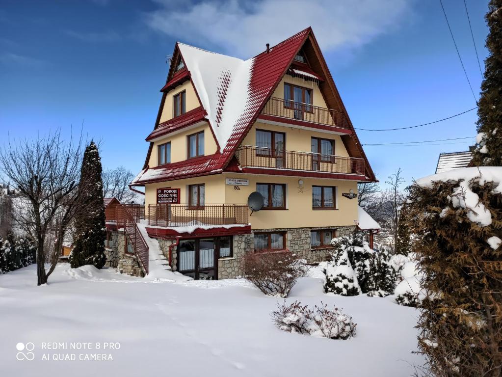 une grande maison avec un toit rouge dans la neige dans l'établissement U Małgorzaty, à Bukowina Tatrzańska