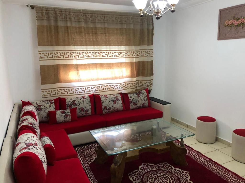 a living room with a red couch and a glass table at Bab Sebta in Fnidek