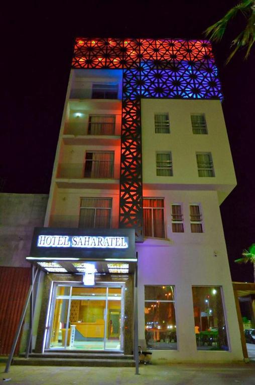 a building with a lit up sign in front of it at Hotel SAHARATEL in Laayoune