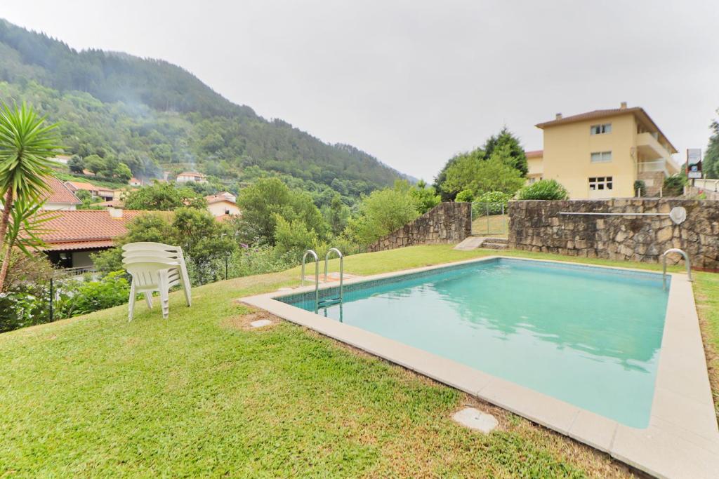 a swimming pool with a chair next to a house at Aparthotel Gerês in Geres