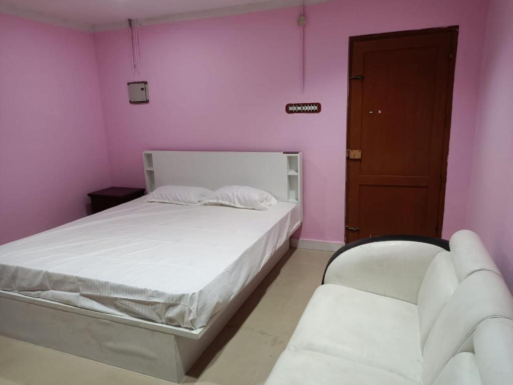 a bedroom with a white bed and a pink wall at Harisuns Plaza in Attingal