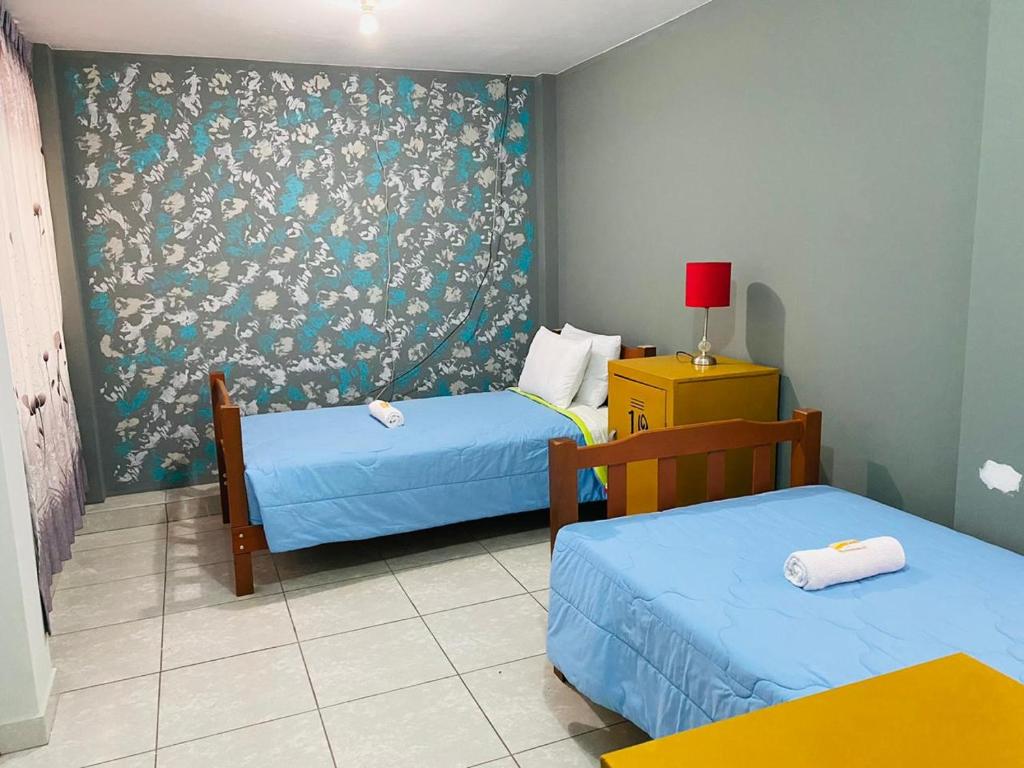 a hotel room with two beds and a wallpaper at Sunset Hostel Airport in Lima