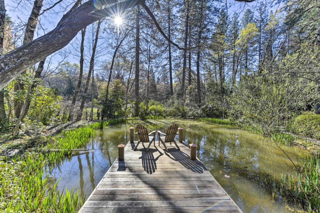 un puente de madera sobre un río con sillas. en Secluded Cottage on 2 and Acres with Pond, Dock and BBQ, en Grass Valley