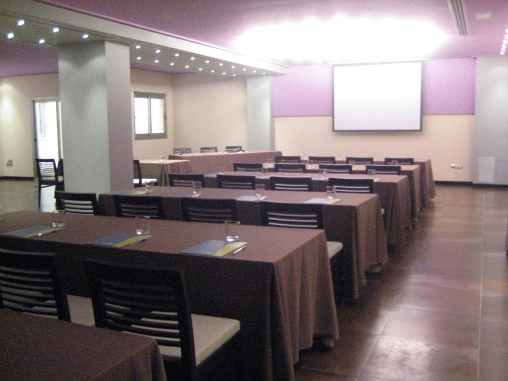 una sala de conferencias con mesas, sillas y una pantalla en Hospedium Hotel Los Periquitos, en Fortuna