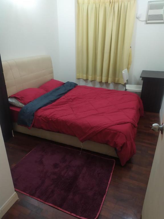 um quarto com uma cama com um edredão vermelho em Seri Maya-Lrt setiawangsa- Medium Room - shared unit em Kuala Lumpur