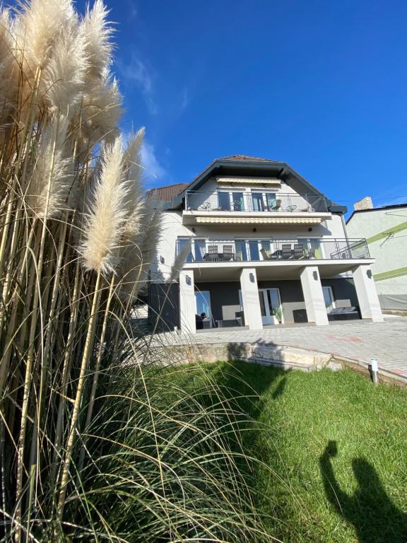 una grande casa bianca con l'erba davanti di Balkon Apartmanház Panzió a Balatonfüred