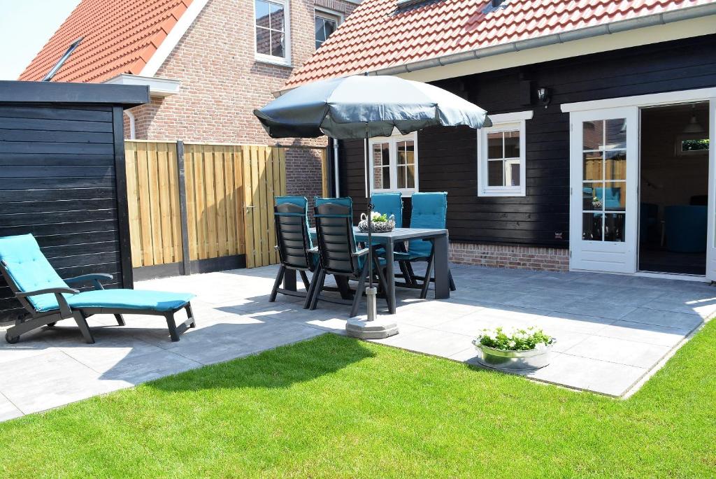 Un patio con una mesa y sillas y una sombrilla. en OK113 Vakantiewoning Zeeduinsepoort 14A met sauna, en Oostkapelle