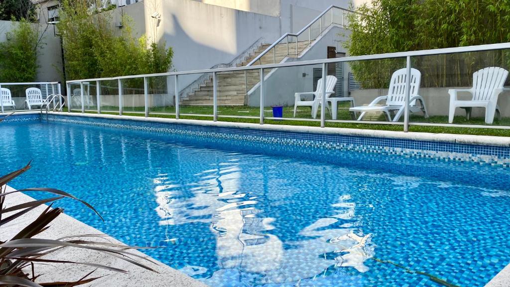 een blauw zwembad met witte stoelen en stoelen bij Palermo Trendy Studio in Buenos Aires