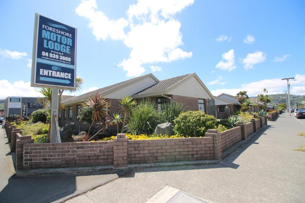 a house with a sign in front of a brick wall at Foreshore Motor Lodge in Petone